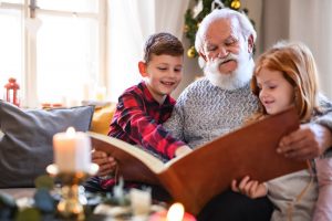 Bearded grandfather sitting with grandkids, looking at pictures and telling stories