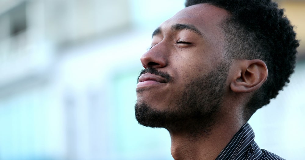 Young african american man thinking with his eyes closed and a smile on his face