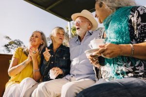 group of older people hanging out, drinking tea, and laughing