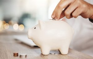 Person putting coin in a piggy bank, preplanning and saving up for future financial needs