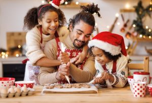 Father baking Christmas cookies with his two young daughters, happy and having fun
