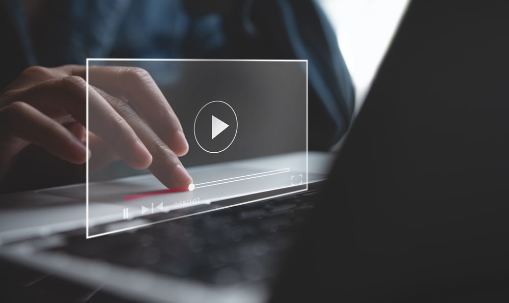 person on a laptop with a video play button in front of them