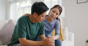 Young Asian couple who are experiencing emotional stress, sitting on the couch at home