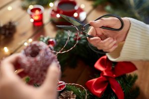 Woman decorating wreath at home with ribbon