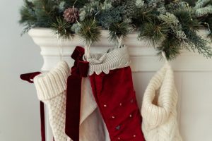 Three knit stockings hanging on the mantel with wreath garland