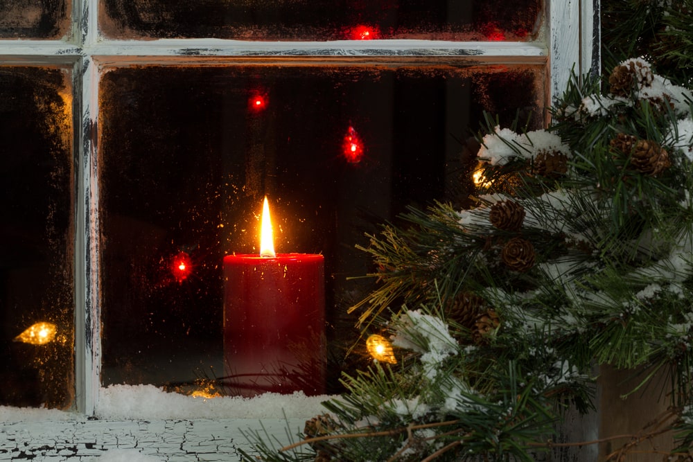 Lit red candle sitting in window in remembrance of a loved one