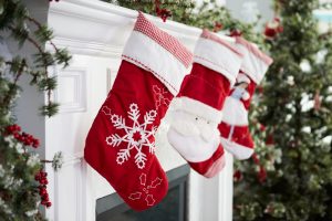 Three red and white Christmas stockings hanging from a mantel