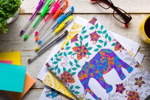 Coloring page with elephant drawn on it, pens and pencils laying on the table nearby