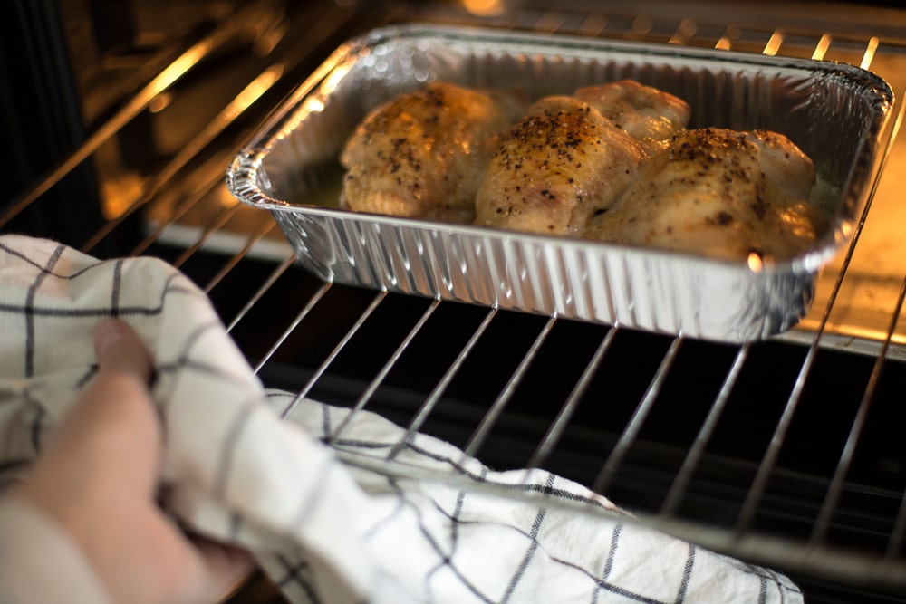 chicken baking in oven in foil pan