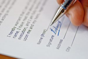 Signing a document, focus on paper and pen