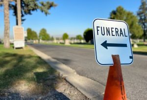 sign by a road on an orange cone that says funeral with an arrow pointing to the left