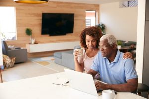 Man and wife at kitchen table with laptop in front of them