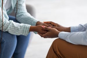 two people holding hands and comforting each other