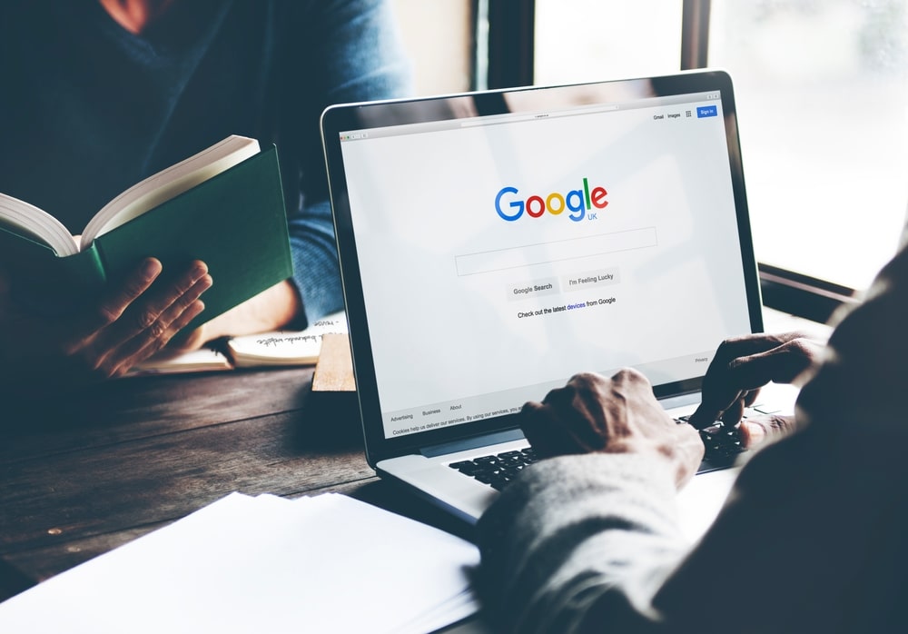 Person sitting at desk in front of a laptop, doing a Google search