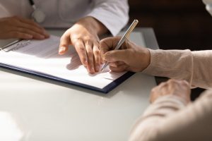 person filling out a form by hand with a pen
