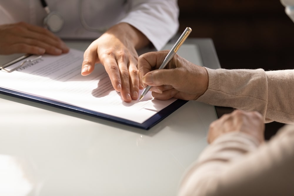 person filling out a form by hand with a pen