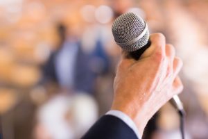 Man holding a microphone as he prepares to speak at a gathering