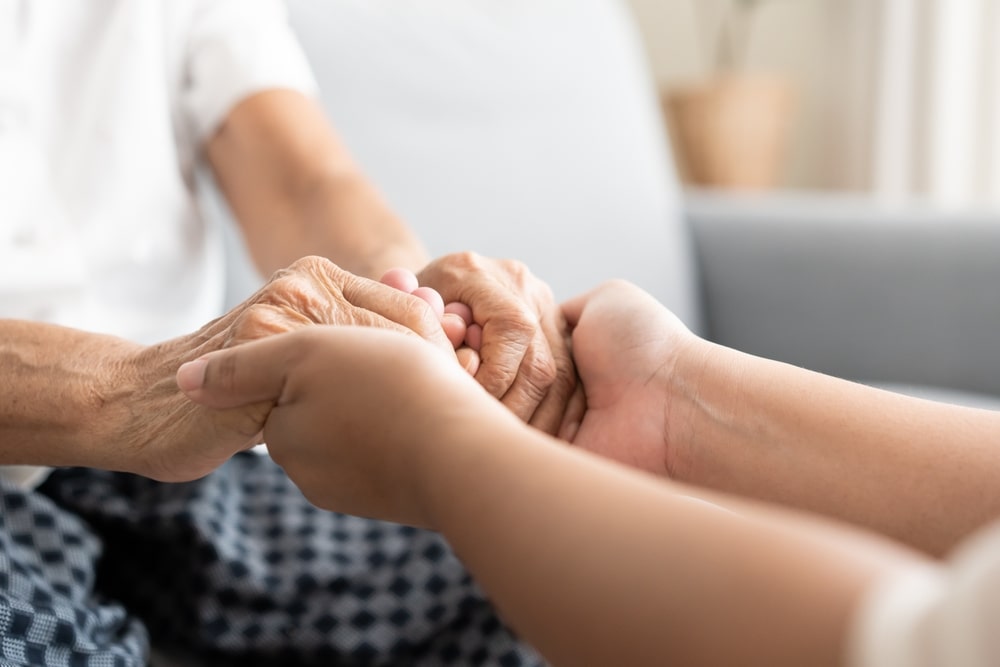 younger woman holding an older person's hands