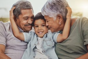 young boy hugging his grandparents as they smile at him