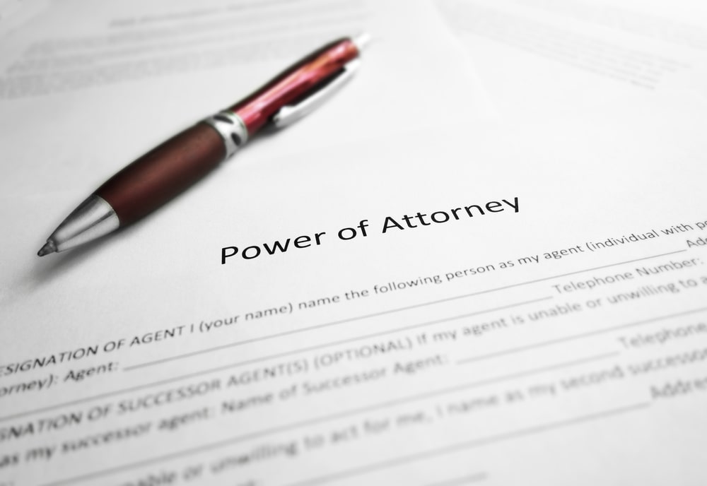 red pen laying on a document that says power of attorney