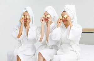 Three women at a spa holding cucumbers over their eyes