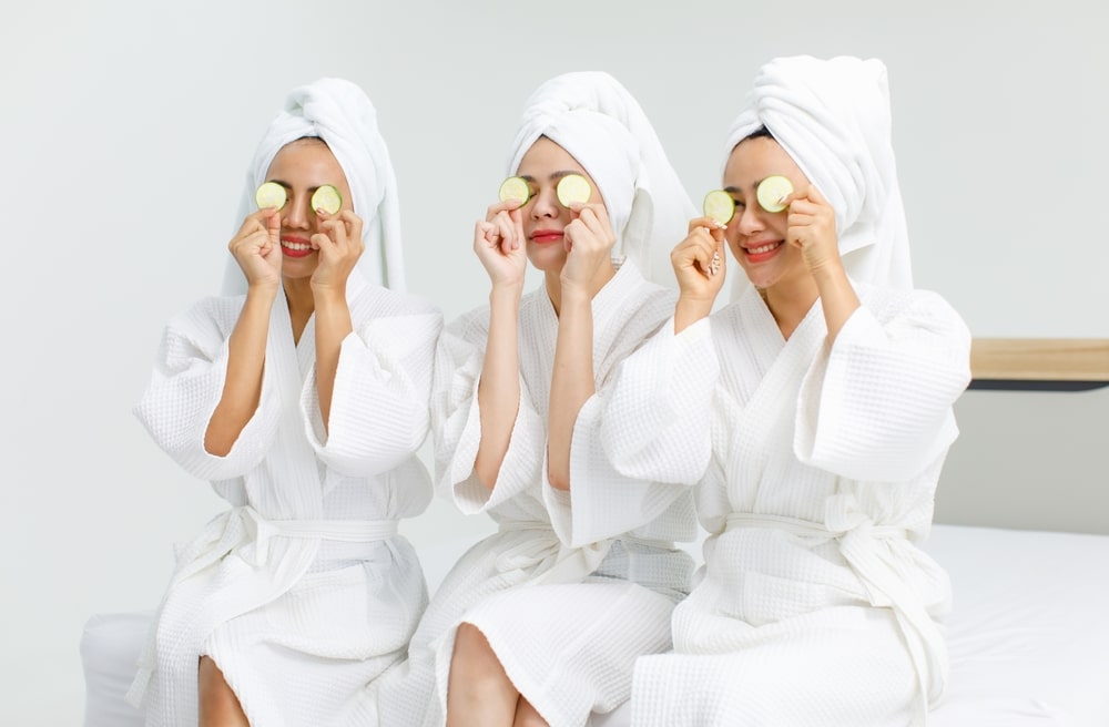 Three women at a spa holding cucumbers over their eyes