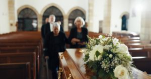 Mature mourners attending a funeral service with casket