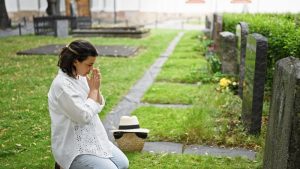 Woman on her knees visiting a loved one's grave
