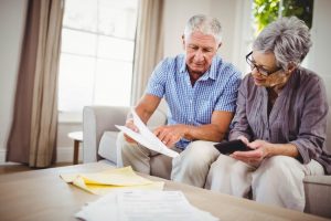 Older couple sitting at home, using a calculator to determine cost; funerals aren't one-size-fits-all