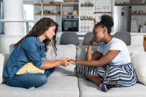 female friend holding another woman's hand as they talk through their grief