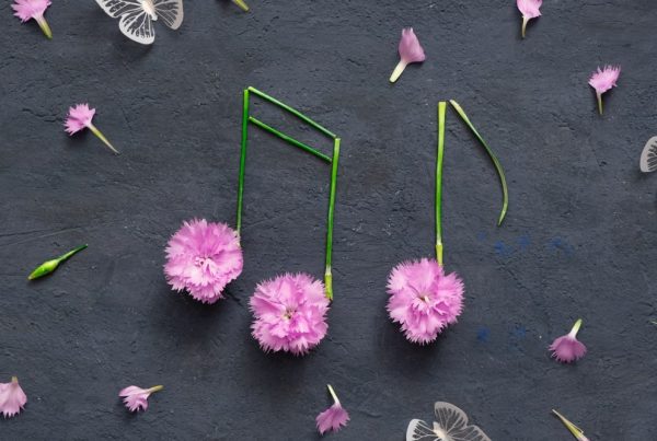 Musical notes made out of pink flowers on black background