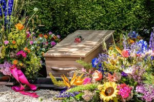 Wooden casket resting outside with flowers all around