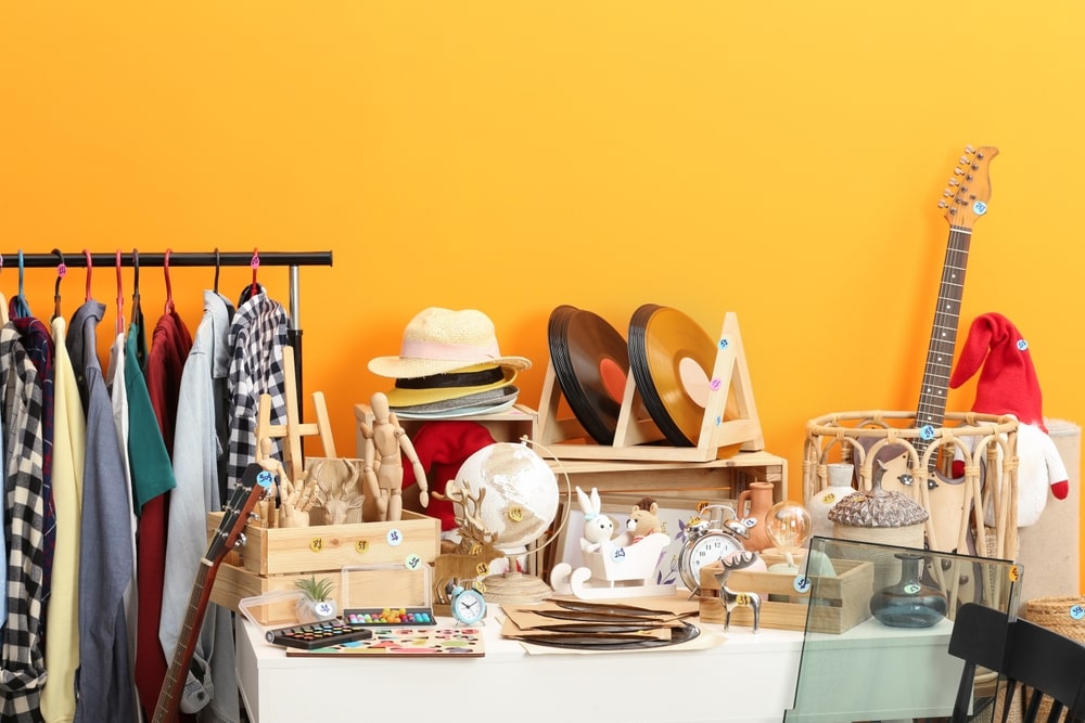 collection of clothes, records, hats, globes, and other estate sale items in front of a yellow wall