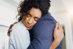 Woman hugging someone in a dark blue shirt for comfort