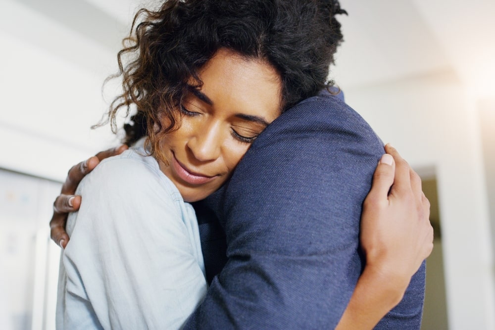 Woman hugging someone in a dark blue shirt for comfort