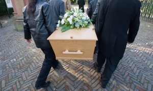 People wearing black carrying a wooden casket