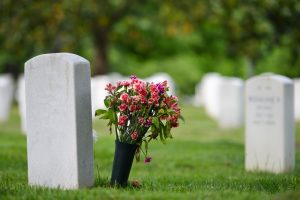 Focus on veteran grave marker with pink flower arrangement next to it
