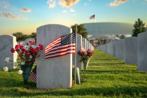 American flag and flower arrangement sitting next to grave markers