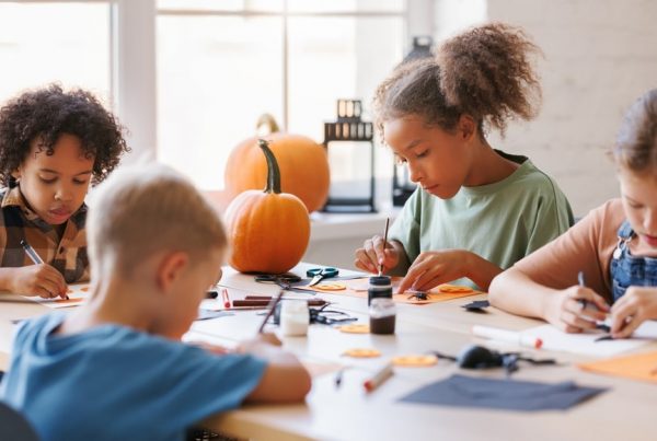 Four children sitting at a table working on fall crafts