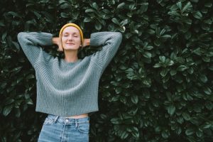 Young woman in yellow beanie hat and sweater standing calming and peacefully