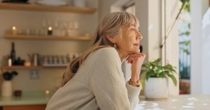 Mature woman looking serenely out the window of her home