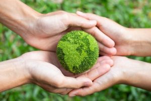 Green earth ball held in the palms of two people