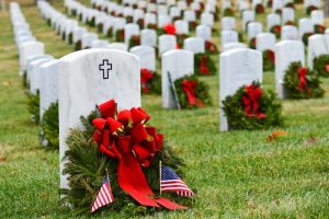 Evergreen wreaths with red bows resting against veteran graves