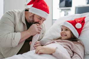 Dad and daughter wearing Christmas hats in a hospital