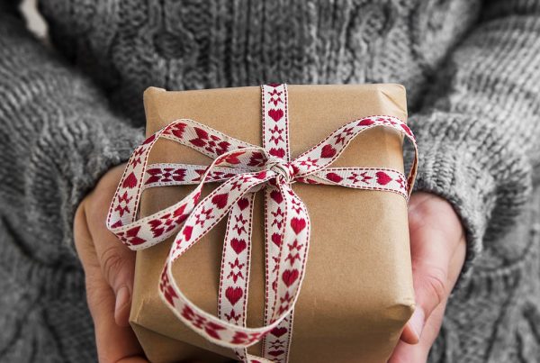 Woman in gray sweater holding wrapped gift