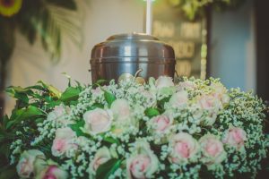 Urn surrounded by pink flowers and greenery. 
