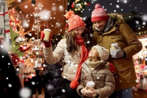 Family of three outside in the snow, enjoying a cup of hot chocolate