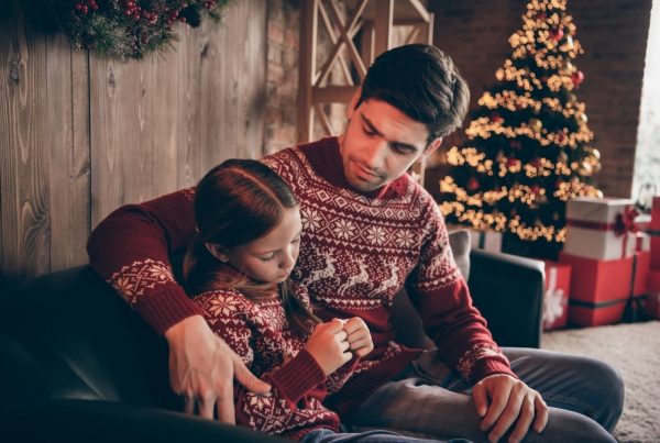 Father sitting next to young daughter, offering comfort at a sad moment