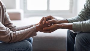 Two people holding each other's hands for comfort