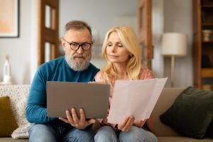 Man and woman sitting on a couch holding files. 
